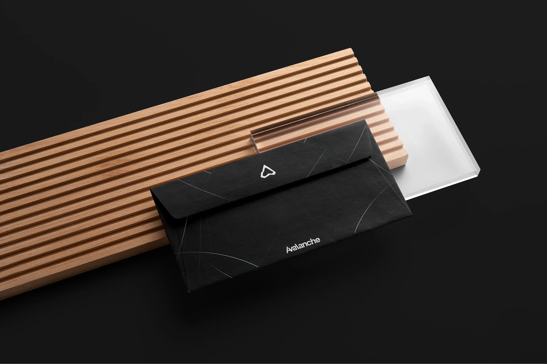 Black envelope and stationery carrying the Avalanche mark on a wooden slat surface